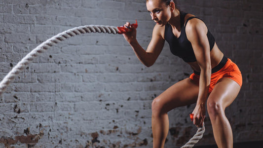Woman swinging a thick piece of rope in the gym